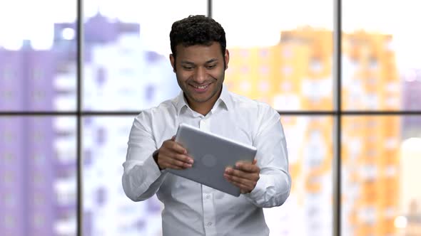 Expressive Emotional Darkskinned Man Plays Games on His Tablet Pc alt