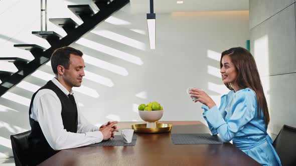 Married Couple Drinking Coffee Early in the Morning at the Table in the Kitchen alt