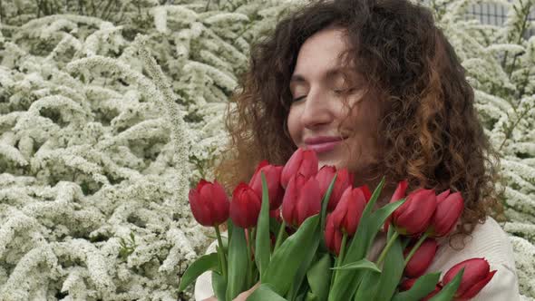 Portrait of a Happy Woman with a Bouquet of Red Tulips