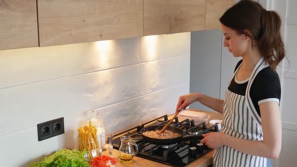 Young Woman in Apron Cooking Healthy Food at Modern Home Kitchen