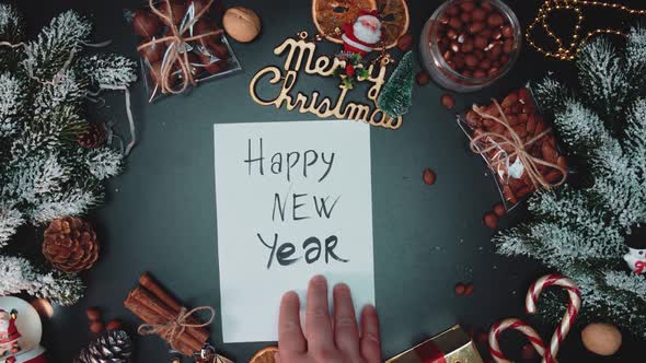 Hands open an envelope with the inscription Happy New Year on a table decorated with 