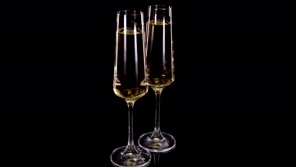Champagne glasses with champagne, rotating on a black background. 