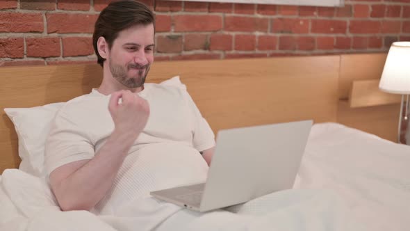 Casual Young Man Having Wrist Pain Working on Laptop in Bed alt