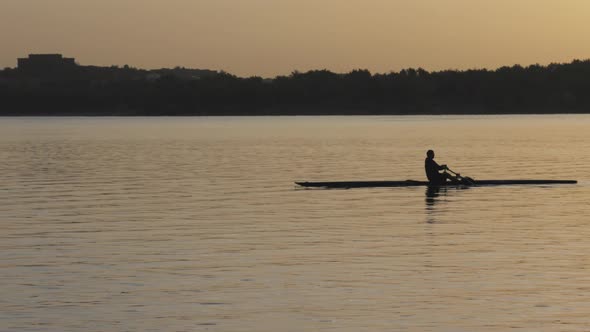 Solo Senior Man Rowing on Lake at Sunrise