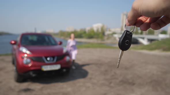In Front of the Camera a Man Waves a Car Key a Happy Girl Runs Up and Takes It and Runs to the Car alt