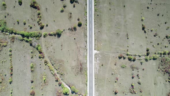 Top Aerial View of an Empty Asphalt Road on the Plateau Between Green Fields alt