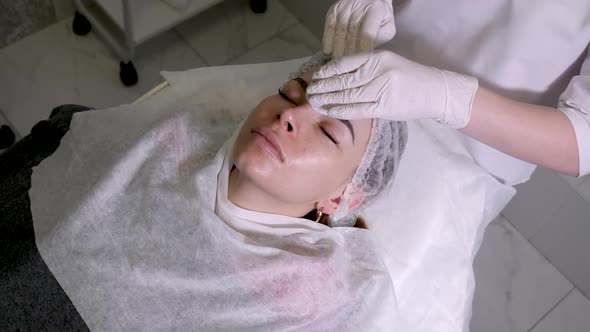 Beautician Smears on the Face Cream Patient Lying on the Couch alt