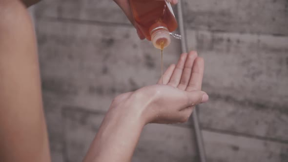 Female Hand Pouring Shampoo Into Palm During Taking a Shower alt