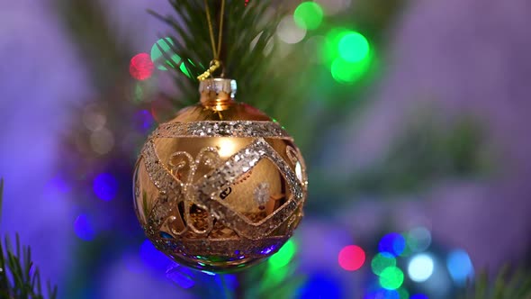 Christmas Tree Decorated with Golden Glass Ball on Christmas Spruce Branch on Background Bokeh of