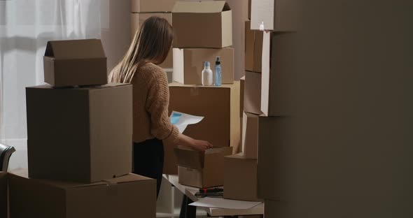 Woman Is Unpackaging Boxes with Cosmetic for Trading Checking Goods in Home Warehouse Reading alt