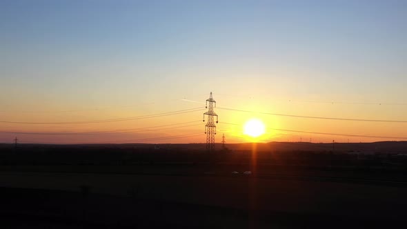 Golden Hour Sunset With Electricity Pylon In Silhouette Against Sunlit Background. wide zoom-in alt