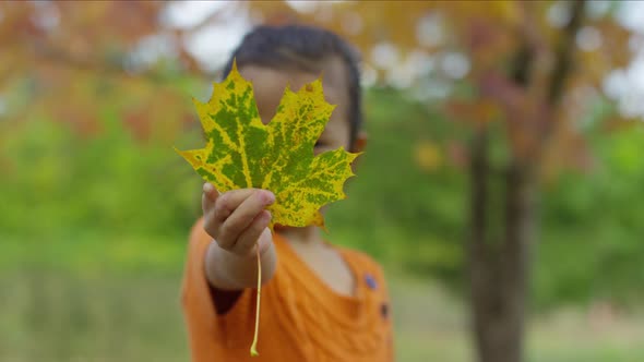 Young girl in Fall holding out leaf