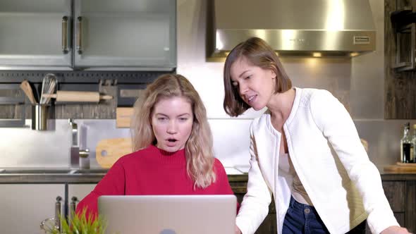 Business women discuss  work project on computer in kitchen home alt