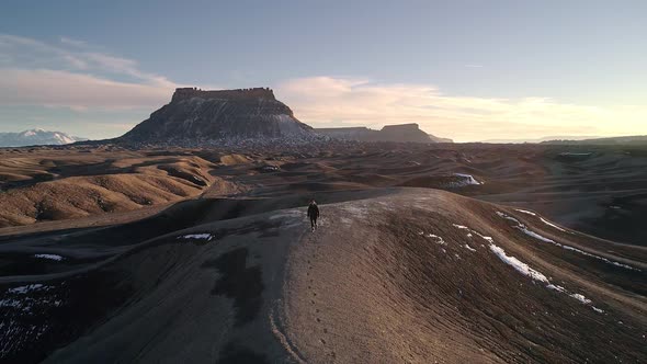 Man lost in the desert following his tracks over sand dune alt