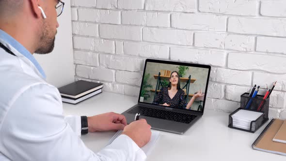 Doctor in hospital office listens patient client writes symptoms in notebook alt