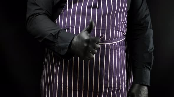 male cook in black uniform and black latex gloves shows like approval gesture