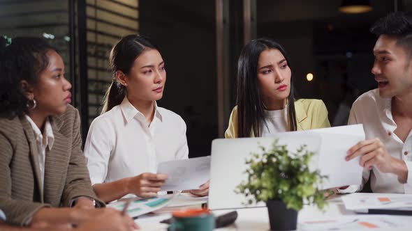 Asian young business people group brainstorming and working on discussion meeting in office at night alt