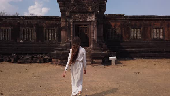 Woman go to ancient palace in Wat Phou ruined Khmer Hindu Temple complex. Laos ancient architecture