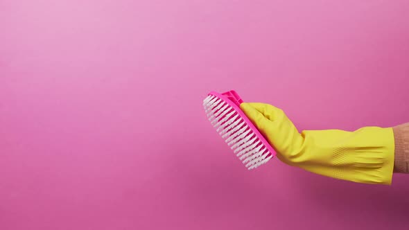 A Hand in a Yellow Rubber Glove with a Pink Plastic Cleaning Brush