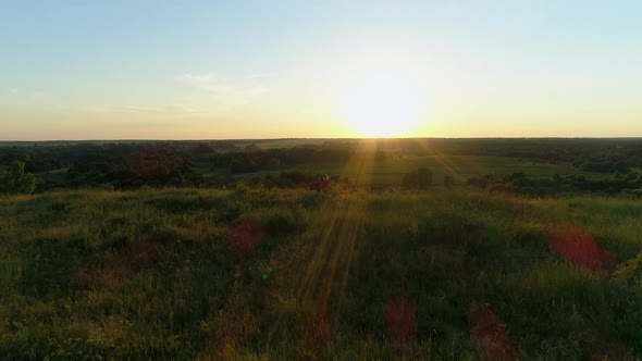 Aerial View Mom and Son Stand on Mountain Cliff Holding Hands Watching Sunset alt