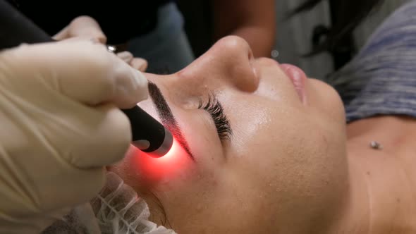 Beautiful Girl Models are Checked for Pigmentation on the Eyebrows Using Special Cosmetology Laser alt