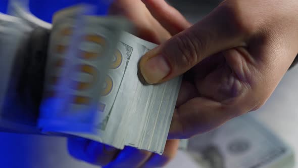 Hands Counting US Dollar Bills or Paying in Cash Against the Backdrop of Police Car Lights alt