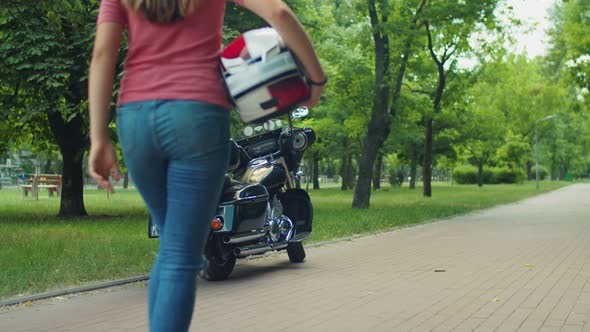 Cute Biker Girl with Helmet Posing By Motorcycle alt