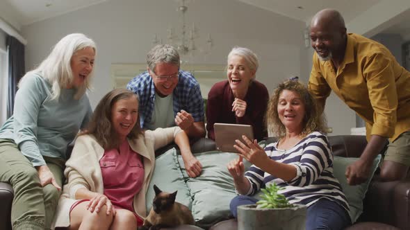Animation of happy diverse female and male senior friends using tablet at home alt