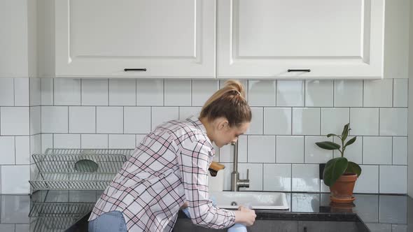 Young Woman Washes Cleaning Kitchen Set with Rag or Cloth