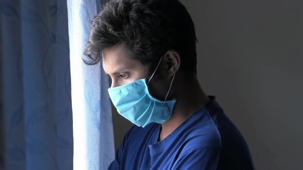 A Young Man with Protective Mask Looking Though Window  alt