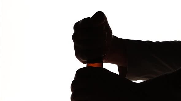 The Silhouette of Male hands opening brown beer bottle