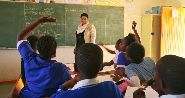 Female teacher and young pupils working in class alt