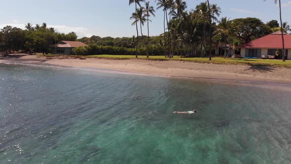 A swimmer snorkels in the clear turquoise water off of Olowalu beach in Maui, Hawaii. alt