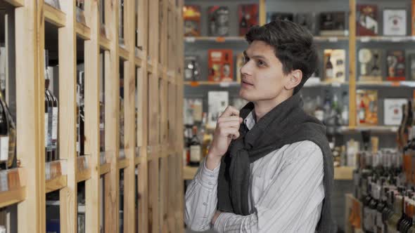Young Handsome Man Smiling to the Camera While Shopping at Wine Store alt