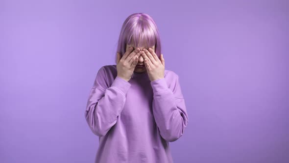 Young Woman Cannot Believe Her Eyes Rubs It and Peers More Closely at Camera on Purple Studio alt