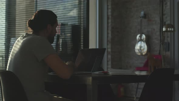 A Young Employee Lingers in the Office After a Working Day alt