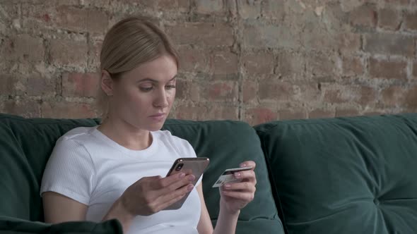 Close-up woman buys online shopping at home with card and phone. alt