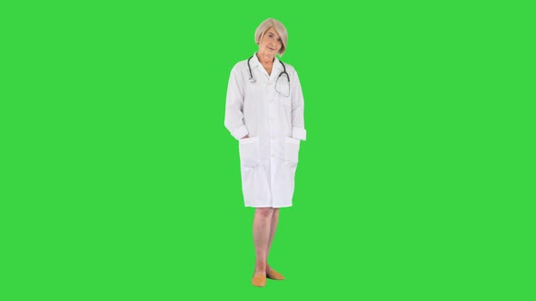 Senior Doctor Standing with Hands Folded and Looking To Camera on a Green Screen Chroma Key alt