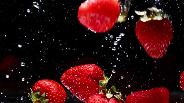 Strawberries Falling Into Slomo Water on Black Background