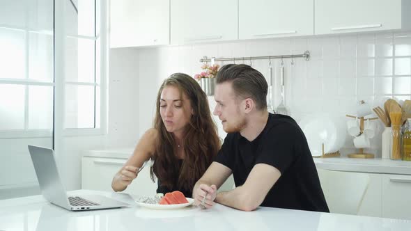 Man and woman with laptop in kitchen alt