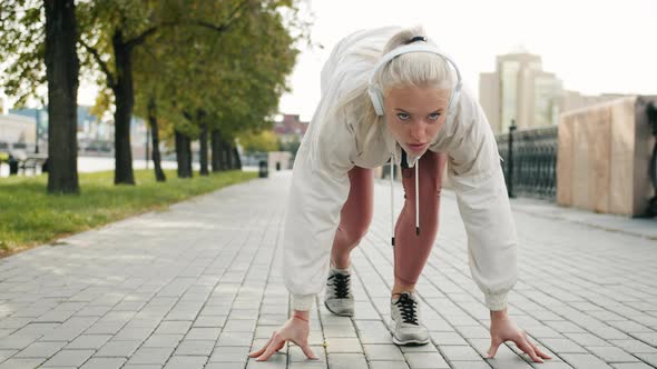 Motivated Sportswoman Getting Ready for Marathon Then Running Fast Wearing Headphones alt
