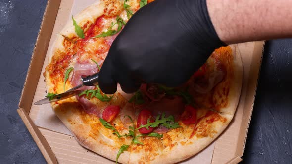 Cutting pizza with a knife in gloves top view. time-lapse