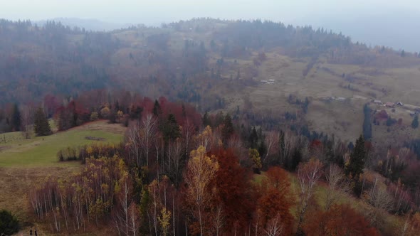 Aerial Drone Footage View: Flight over autumn mountain with forests and fields