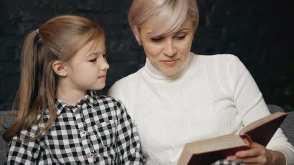 Female Spending Free Time and Reading Book with Her Child