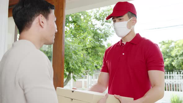 Young postal delivery courier man wear face mask handling food box for send to customer at house.