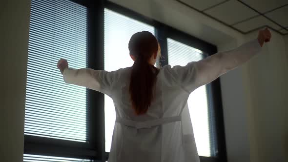Closeup Lowangle View of Unrecognizable Female Doctor Wearing White Coat Stretching Hands on alt