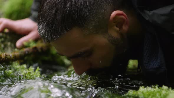 The Close Up of a Tourist with a Backpack Drinks the Lifegiving Water From a Clean River