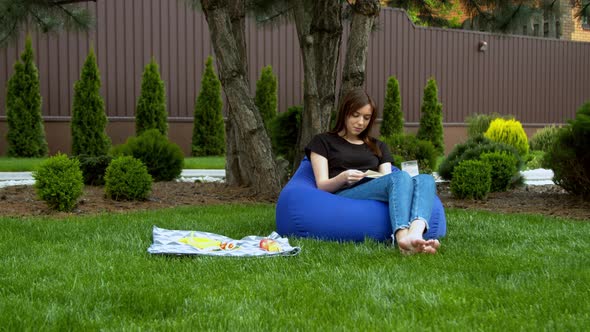 Young Woman Reading Book in Garden