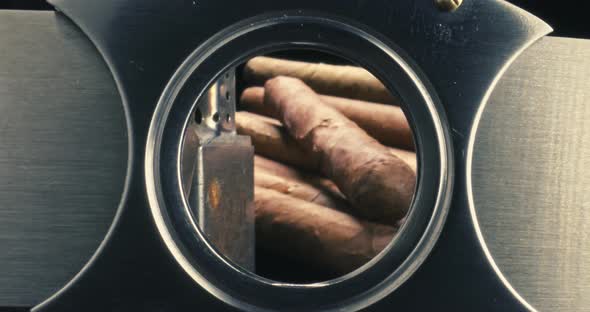 View through a cigar cutter. Cigars in humidor and lighter. alt