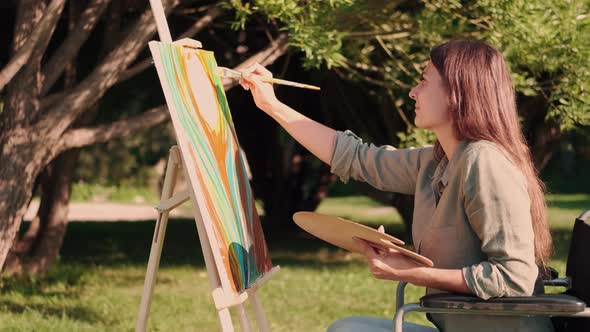A Disabled Woman in a Wheelchair Paints a Picture in the Park alt
